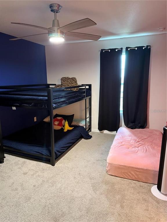 A bedroom features a black metal bunk bed, a pink floor mattress, and a ceiling fan — 2489 BLOWING BREEZE AVENUE, KISSIMMEE, FL