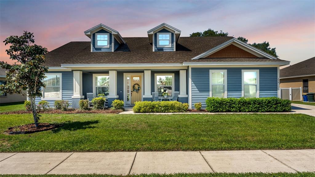 A blue, single-story house with a front porch, two dormer windows, and a grassy lawn — 254 KISSENGEN PARK DRIVE, BARTOW, FL