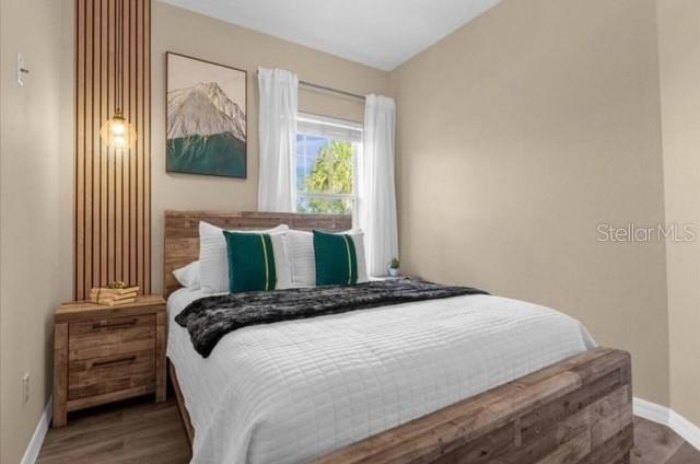 A bedroom features a wooden bed frame, a matching nightstand, and a vertical slat accent wall — 2847 OAKWATER DRIVE UNIT 2847, KISSIMMEE, FL