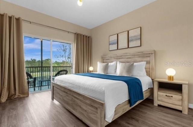 A bedroom with a wooden bed frame, beige walls, and a sliding glass door view — 2847 OAKWATER DRIVE UNIT 2847, KISSIMMEE, FL