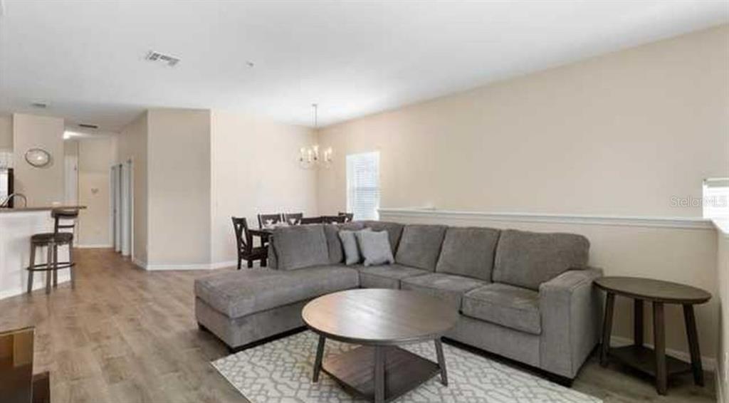 A living room features a gray sectional sofa, a round wooden coffee table, and wood-look flooring — 2847 OAKWATER DRIVE UNIT 2847, KISSIMMEE, FL