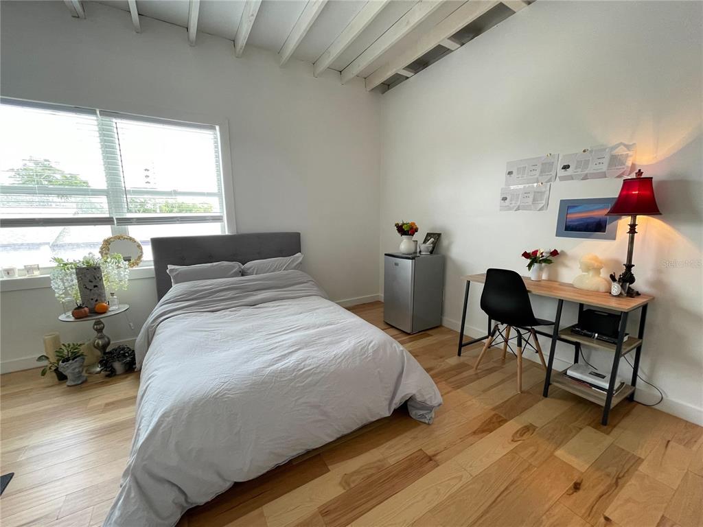 A bedroom features a gray bed, a desk with a lamp, and light wood flooring — 1619 9TH AVENUE N, ST PETERSBURG, FL