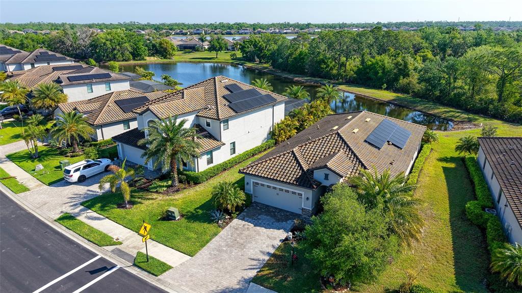 An aerial view shows two suburban houses with tile roofs and solar panels near water — 17241 BLUE RIDGE PLACE, BRADENTON, FL