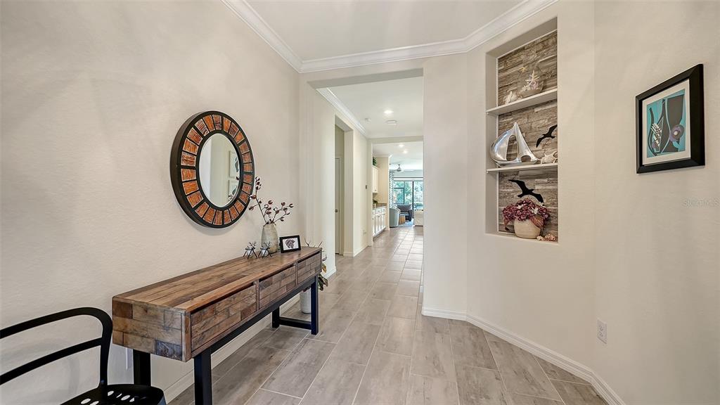 A foyer features a wooden console table, a round mirror, and a built-in wall niche — 17241 BLUE RIDGE PLACE, BRADENTON, FL