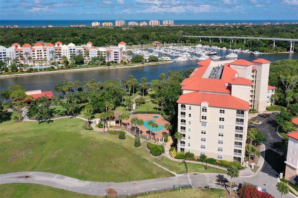 An aerial view shows a multi-story building with a red roof, pool, and marina — 146 PALM COAST RESORT BOULEVARD UNIT 405, PALM COAST, FL