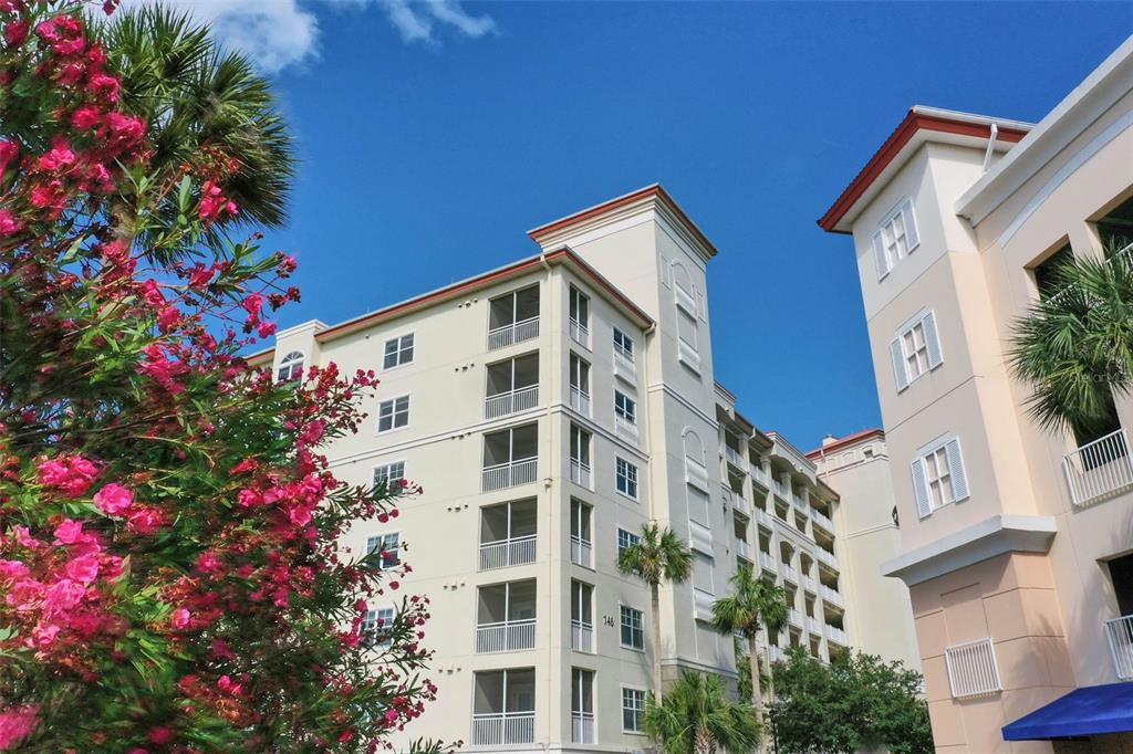 A multi-story apartment building with screened balconies stands under a clear blue sky — 146 PALM COAST RESORT BOULEVARD UNIT 405, PALM COAST, FL