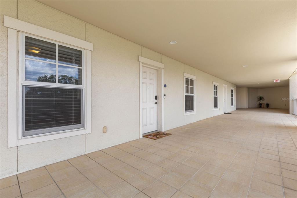 A long, covered outdoor walkway features light-colored tiled flooring and several white exterior doors — 146 PALM COAST RESORT BOULEVARD UNIT 405, PALM COAST, FL