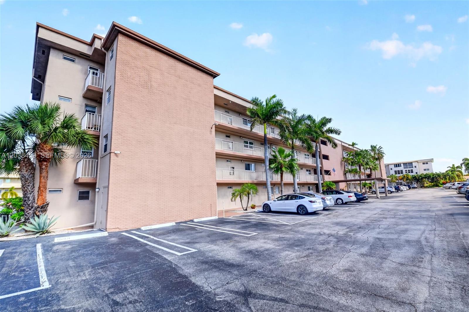 A multi-story apartment building with a parking lot and palm trees in front — 2615 NE 1st Ct # 303, Boynton Beach FL 33435, BOYNTON BEACH, FL