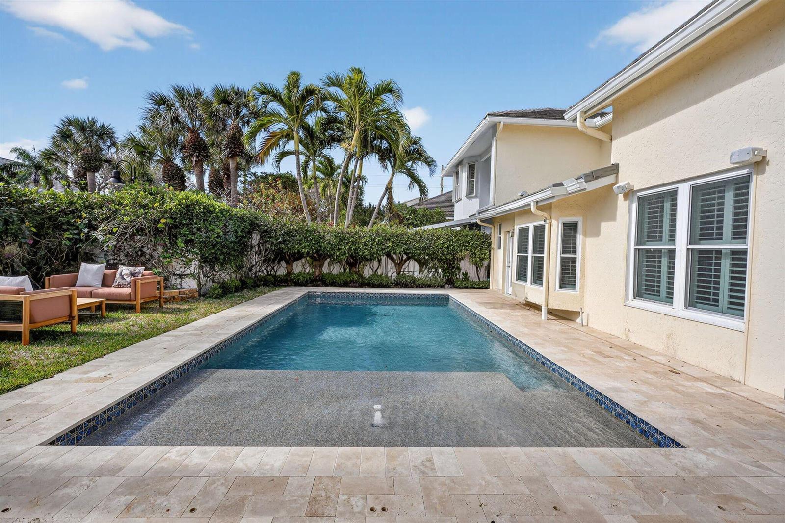 A rectangular swimming pool with a tanning ledge sits beside a house with beige siding — 3069 Mainsail Circle, Jupiter FL 33477, JUPITER, FL