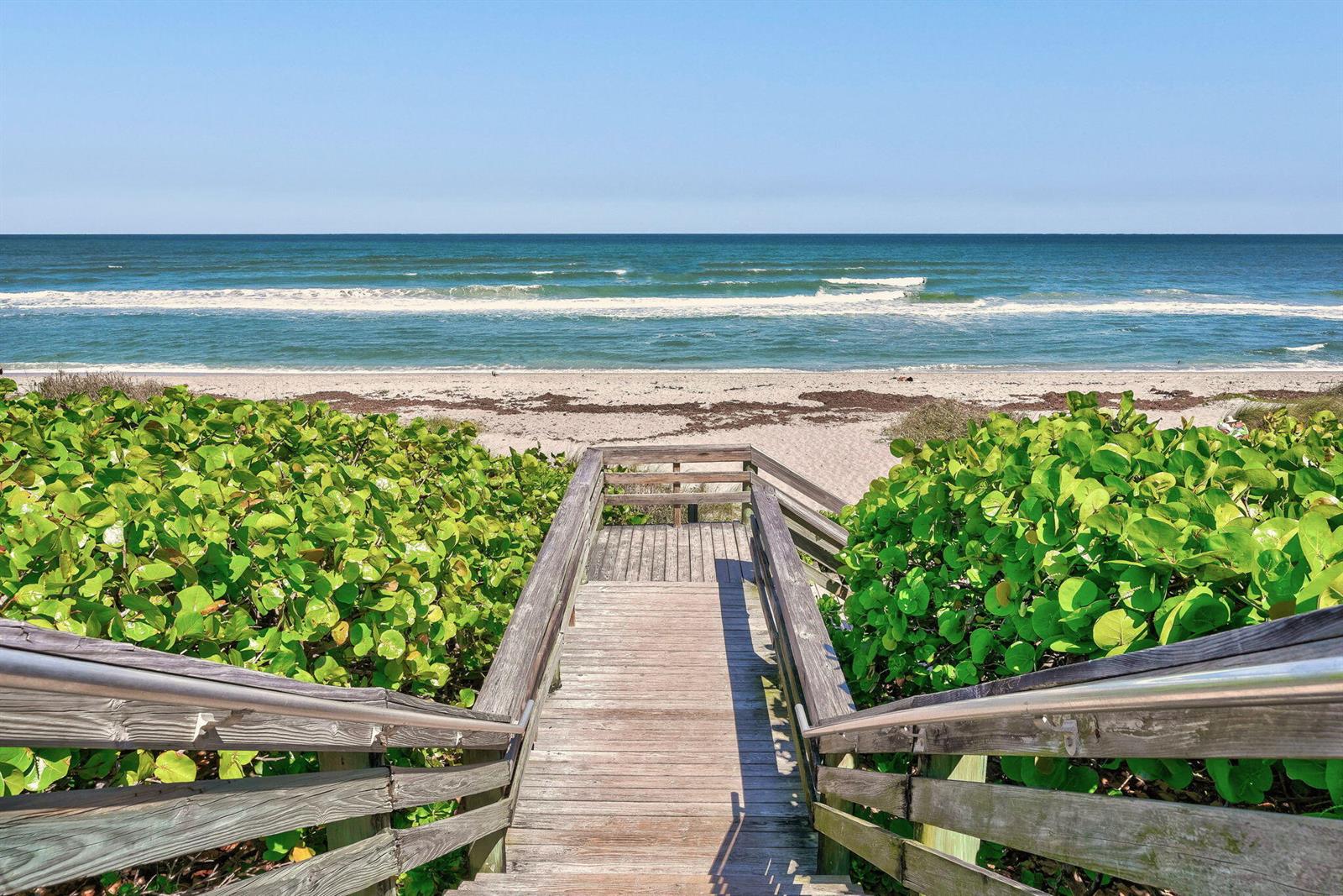 A wooden staircase leads through green shrubs to a sandy beach and the ocean — 3069 Mainsail Circle, Jupiter FL 33477, JUPITER, FL