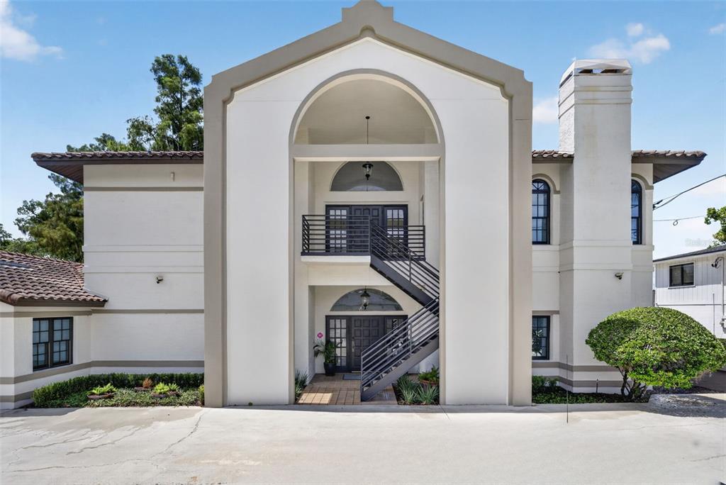 A two-story building exterior features a central arched entryway with an external metal staircase — 1477 W FAIRBANKS AVENUE, WINTER PARK, FL