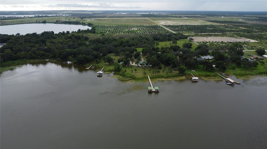 An aerial view shows a lakefront property with multiple docks and surrounding agricultural fields — 742 N LAKE REEDY BOULEVARD, FROSTPROOF, FL