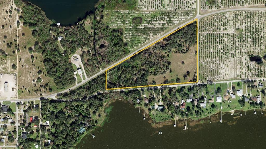 An aerial view shows a triangular plot of land outlined in yellow near a lake — 742 N LAKE REEDY BOULEVARD, FROSTPROOF, FL