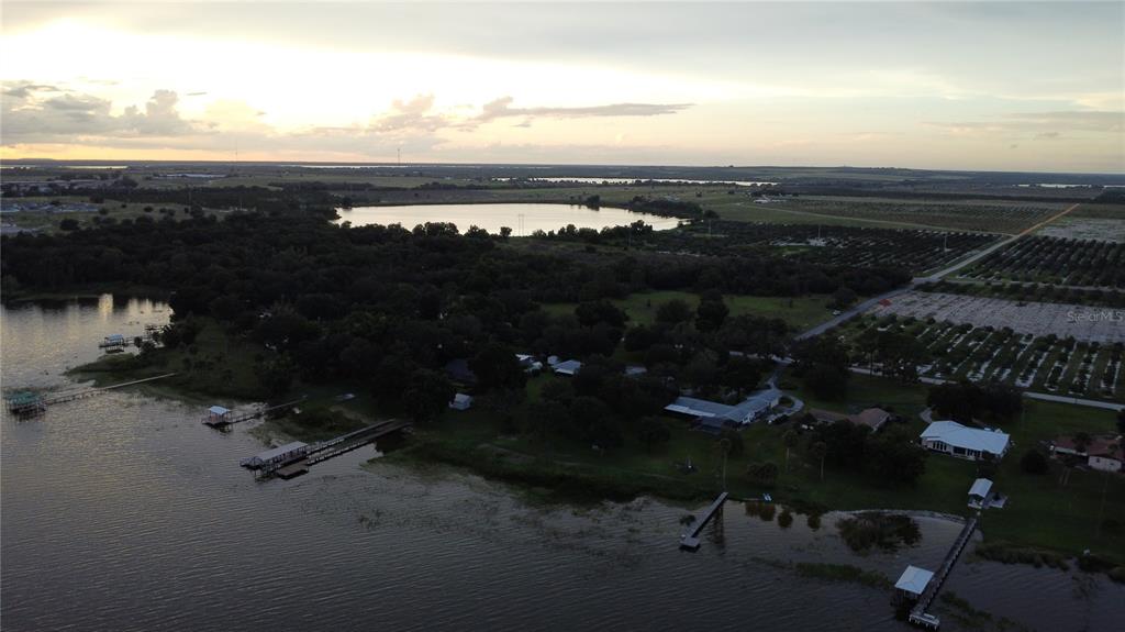 An aerial view shows a lakefront property with several houses, docks, and nearby agricultural fields — 742 N LAKE REEDY BOULEVARD, FROSTPROOF, FL