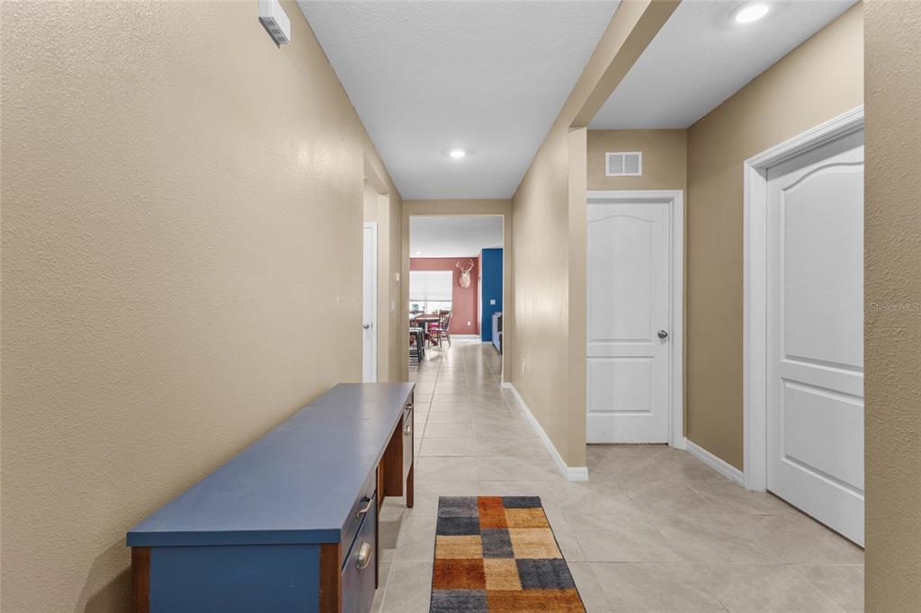 A hallway with beige walls, tile flooring, a blue desk, and two white doors — 3637 DIVING DOVE LANE, BARTOW, FL