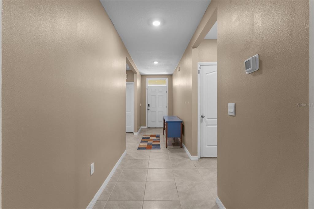 A tiled hallway leads to a front door with a transom window and side table — 3637 DIVING DOVE LANE, BARTOW, FL