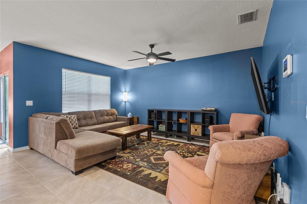 A living room features blue walls, a sectional sofa, two armchairs, and a ceiling fan — 3637 DIVING DOVE LANE, BARTOW, FL