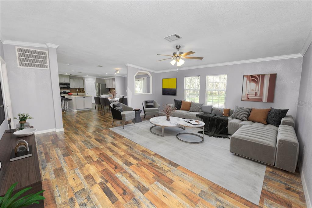A living room with wood-look flooring, a sectional sofa, and an open-concept kitchen beyond — 7405 SHOUPE ROAD, PLANT CITY, FL