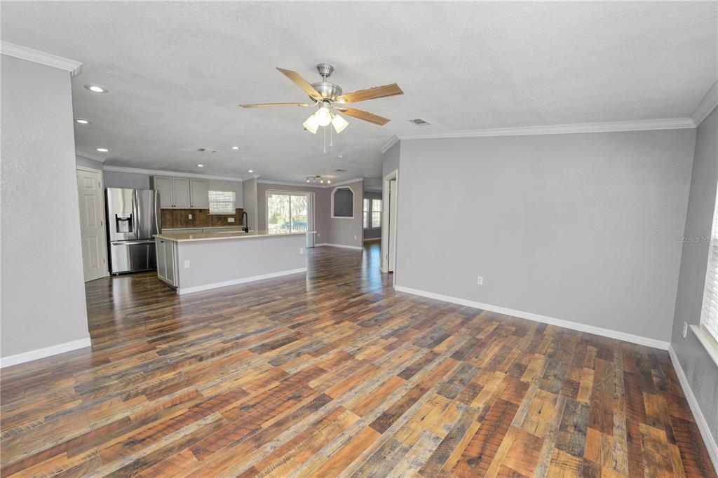 An open-concept living room and kitchen featuring wood-look flooring and a ceiling fan — 7405 SHOUPE ROAD, PLANT CITY, FL