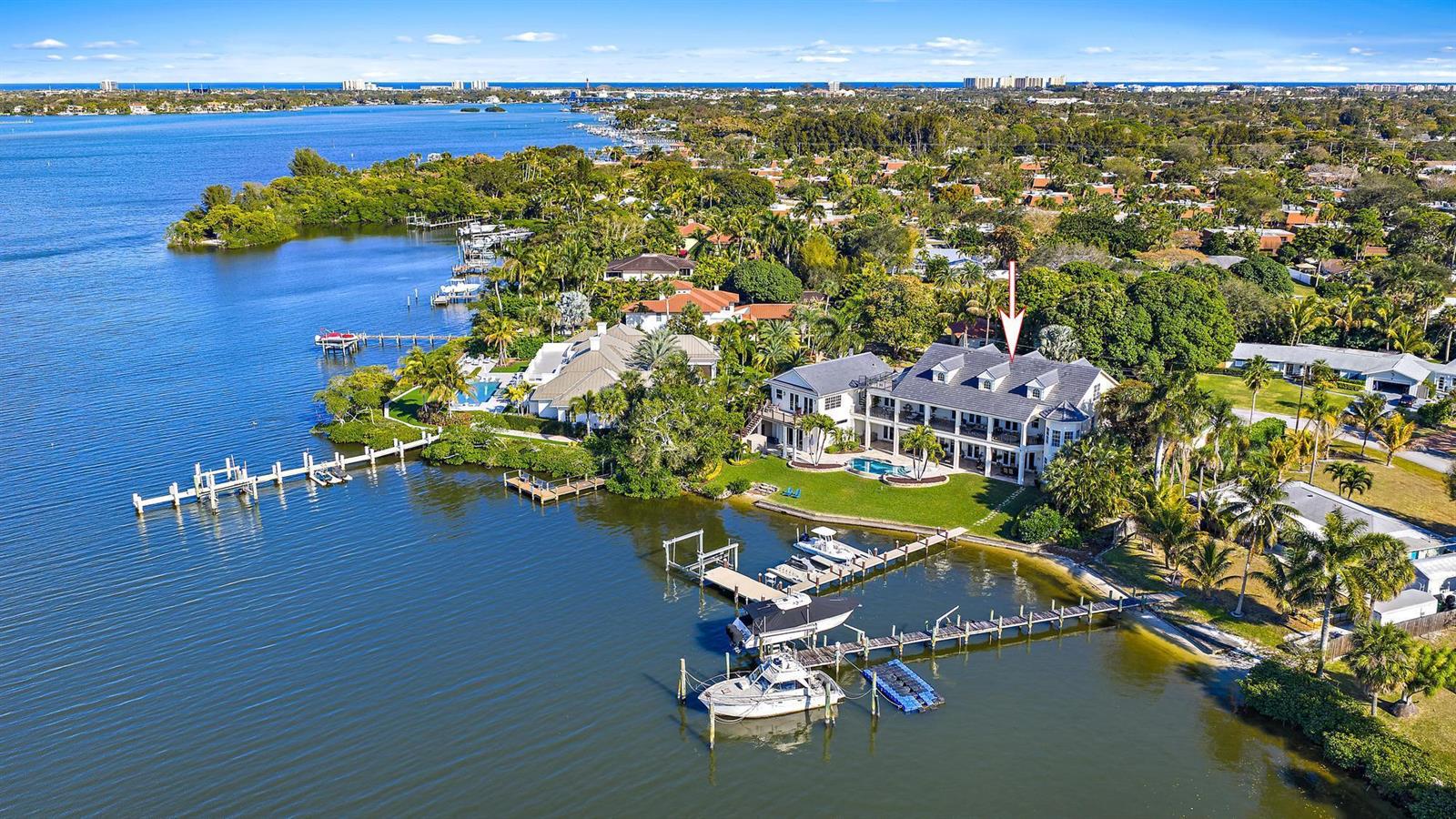 An aerial view of a large waterfront house with a private dock and multiple boats — 18137 Palm Point Drive, Jupiter FL 33458, JUPITER, FL