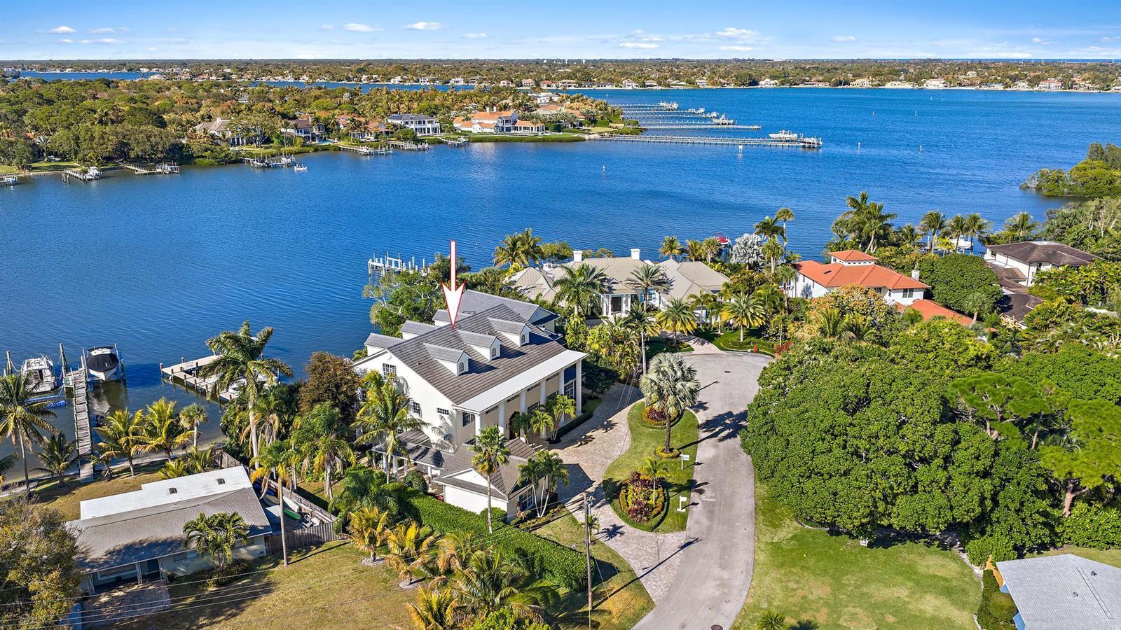 An aerial view shows a large waterfront house with a gray roof and palm trees — 18137 Palm Point Drive, Jupiter FL 33458, JUPITER, FL