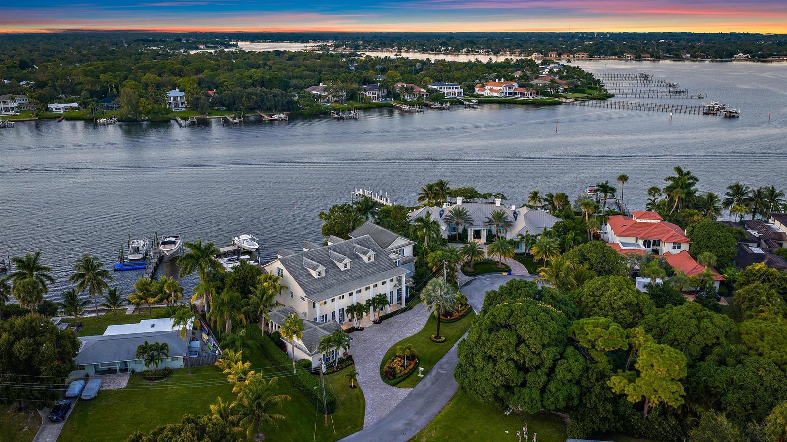 An aerial view of a waterfront estate featuring a large house, boat docks, and landscaping — 18137 Palm Point Drive, Jupiter FL 33458, JUPITER, FL