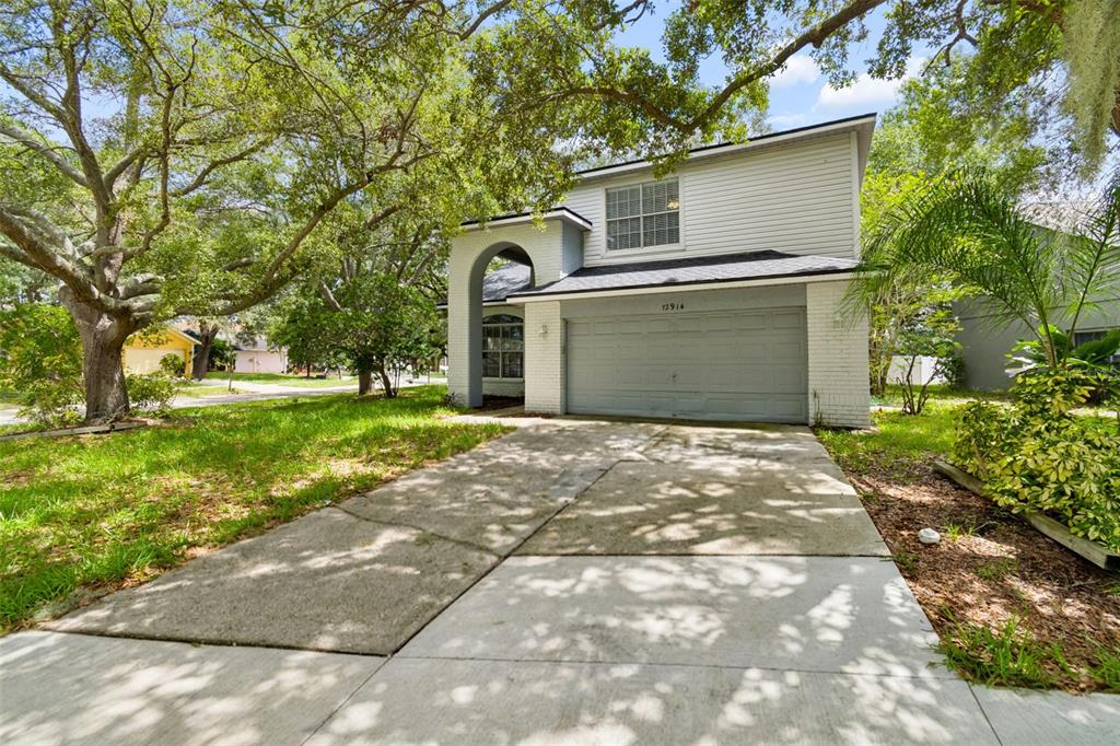 A two-story house with a gray garage, white brick accents, and a concrete driveway — 12914 LONGCREST DRIVE, RIVERVIEW, FL