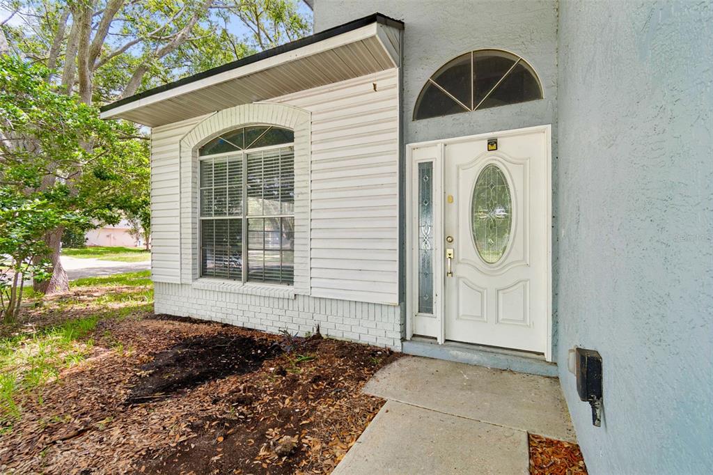 The exterior of a house features a white front door, a window, and light-colored siding — 12914 LONGCREST DRIVE, RIVERVIEW, FL