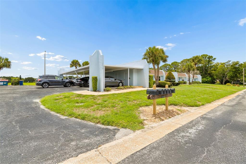 A light blue single-story building features a covered carport and a row of mailboxes — 11110 CARRIAGE HILL DRIVE UNIT 5, PORT RICHEY, FL