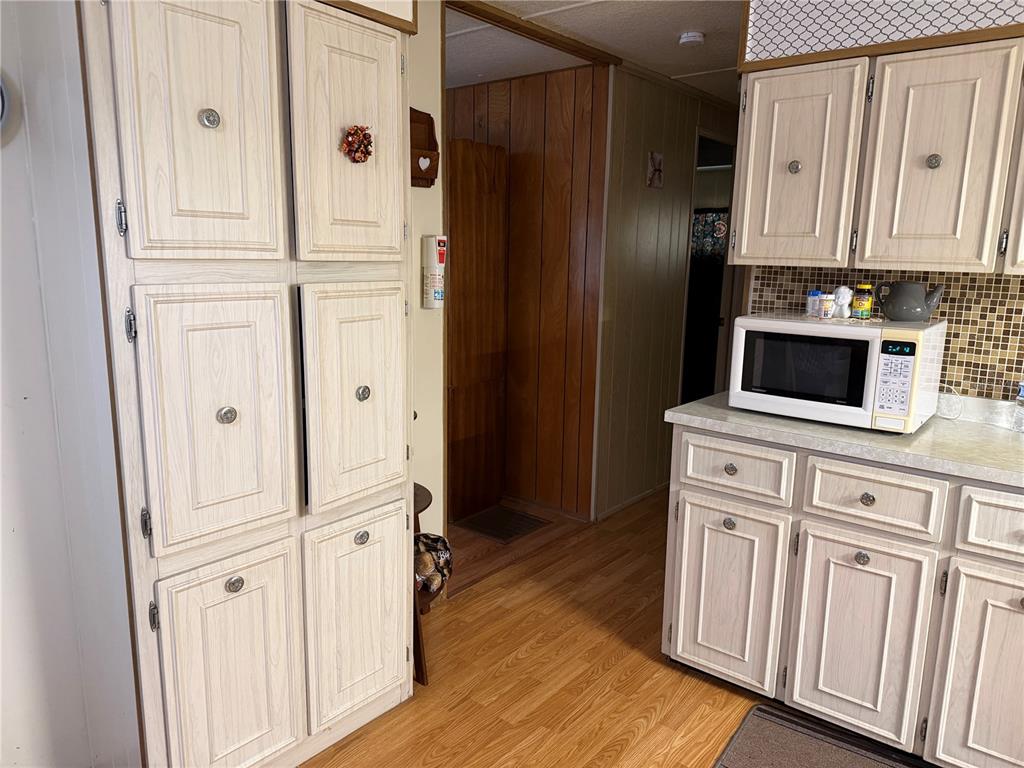 A kitchen features light wood cabinets, a microwave on the counter, and wood-look flooring — 2044 HOYLE DRIVE, HOLIDAY, FL