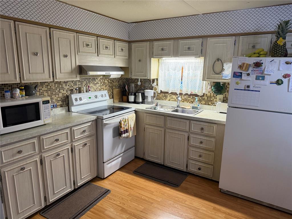 A kitchen features light wood cabinets, a white stove, a microwave, and a white refrigerator — 2044 HOYLE DRIVE, HOLIDAY, FL