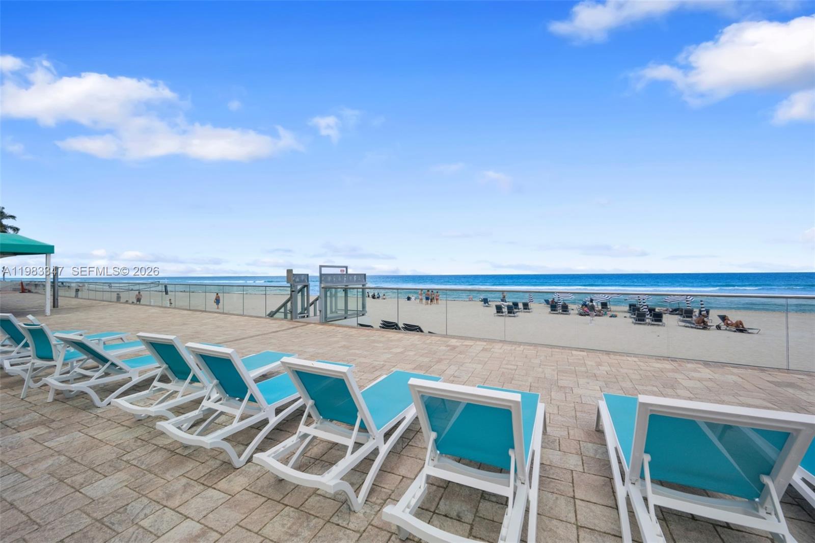 A paved patio features rows of turquoise lounge chairs overlooking a sandy beach and ocean — 3725 S Ocean Dr # 924, Hollywood FL 33019, HOLLYWOOD, FL