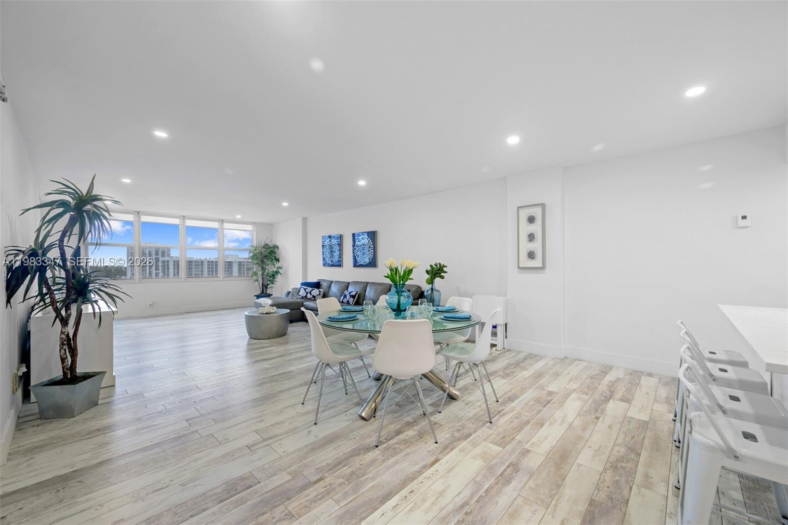 An open-concept living and dining area features light wood-look flooring and floor-to-ceiling windows — 3725 S Ocean Dr # 924, Hollywood FL 33019, HOLLYWOOD, FL