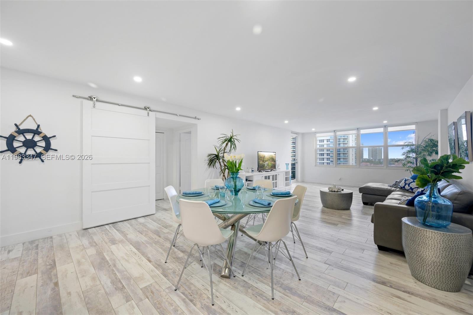A bright living and dining area features white walls, light wood-look flooring, and a glass-topped table — 3725 S Ocean Dr # 924, Hollywood FL 33019, HOLLYWOOD, FL