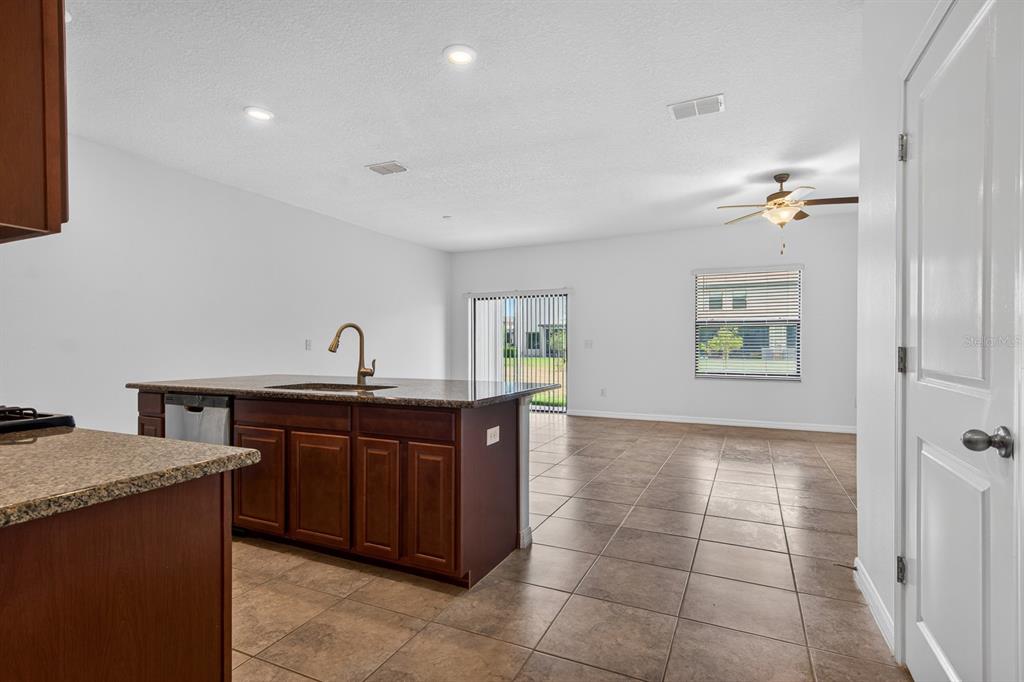 A kitchen island with a sink sits in an open-concept room with tile flooring — 3488 PINE RIBBON DRIVE, LAND O LAKES, FL