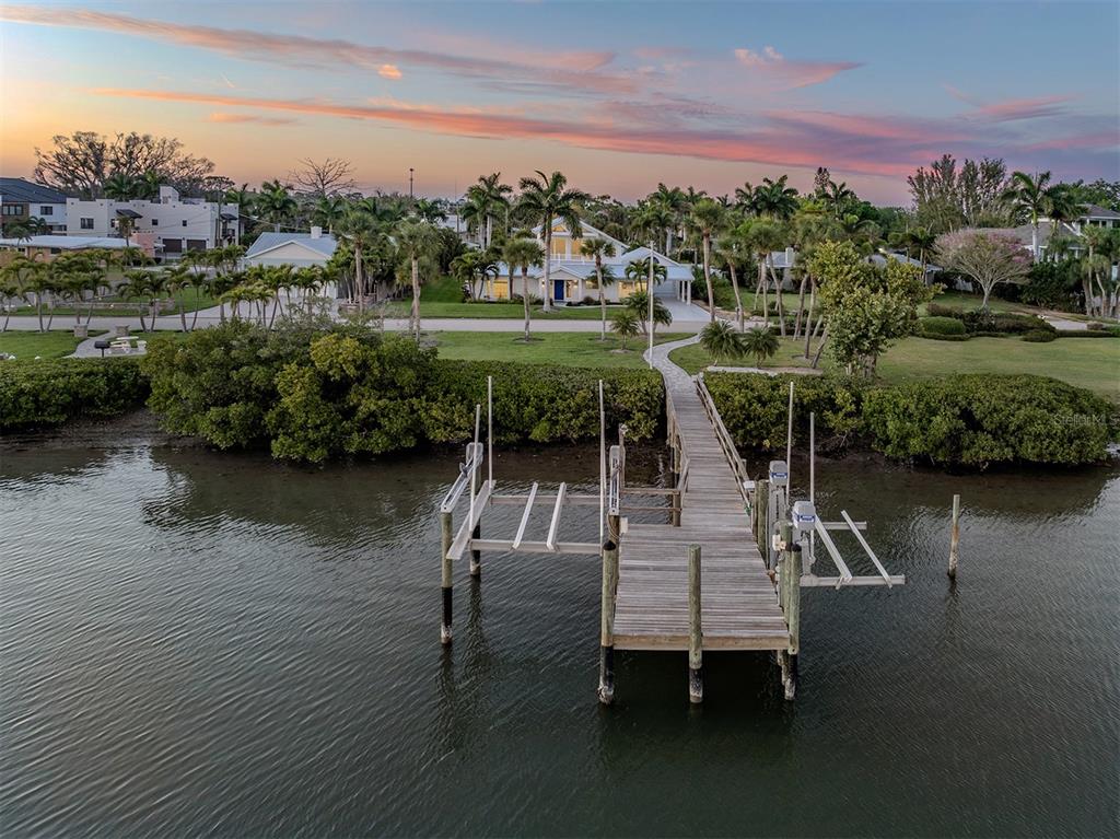 An aerial view shows a wooden dock extending into the water toward a coastal house — 212 SUNRISE DRIVE, NOKOMIS, FL