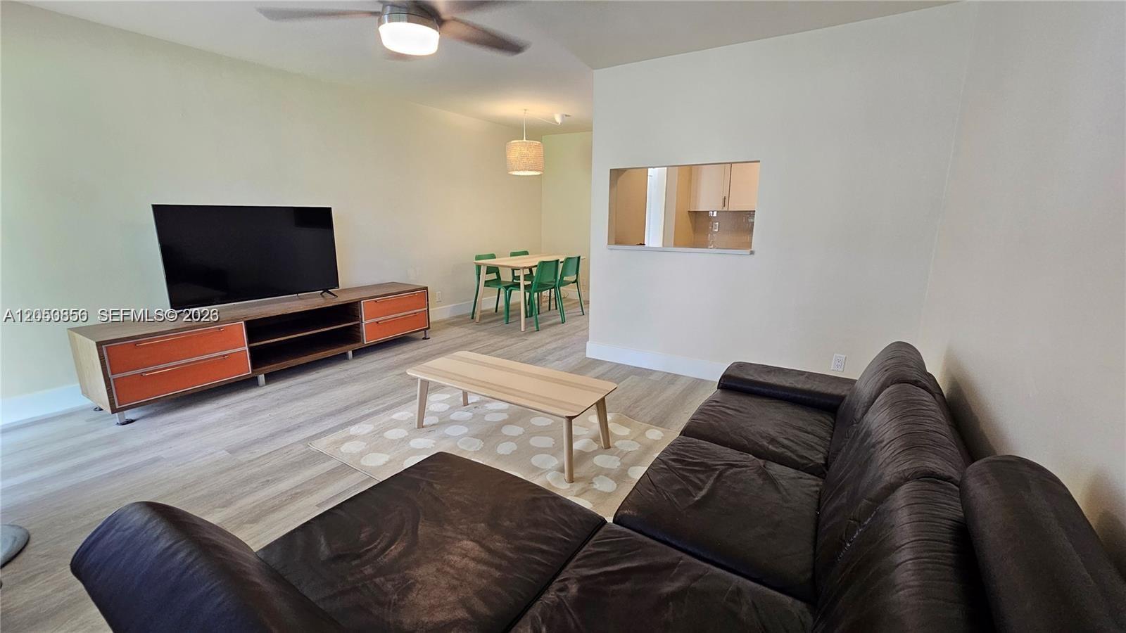 A living room features a dark leather sectional, a television console, and a dining area — HOLLYWOOD, FL