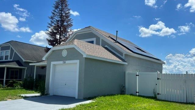 A gray detached garage with a white door and solar panels on the roof — 728 BELVOIR DRIVE, DAVENPORT, FL