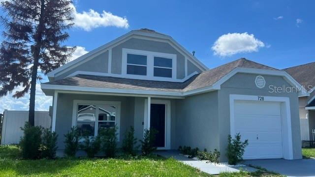 A single-story house with a gray exterior, a front-facing garage, and a large pine tree — 728 BELVOIR DRIVE, DAVENPORT, FL