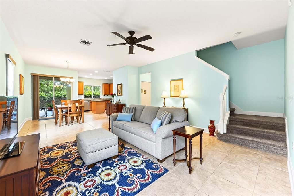 A living room with a gray sofa, patterned rug, and stairs leading to an upper level — 5585 RUTHERFORD PLACE, OVIEDO, FL
