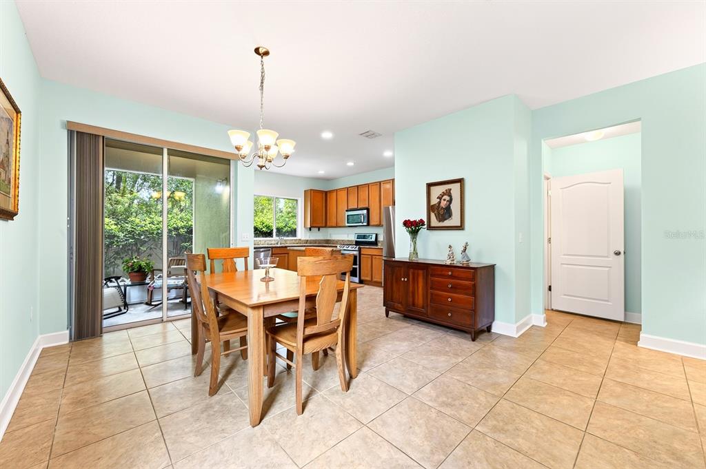 A dining area with a wooden table, chairs, tile flooring, and an adjacent kitchen — 5585 RUTHERFORD PLACE, OVIEDO, FL