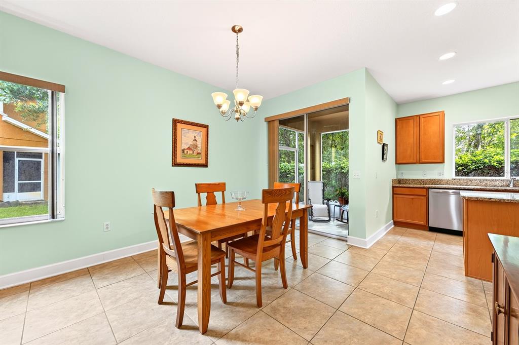 A dining area with tile floors, a wooden table, and a sliding door to a patio — 5585 RUTHERFORD PLACE, OVIEDO, FL