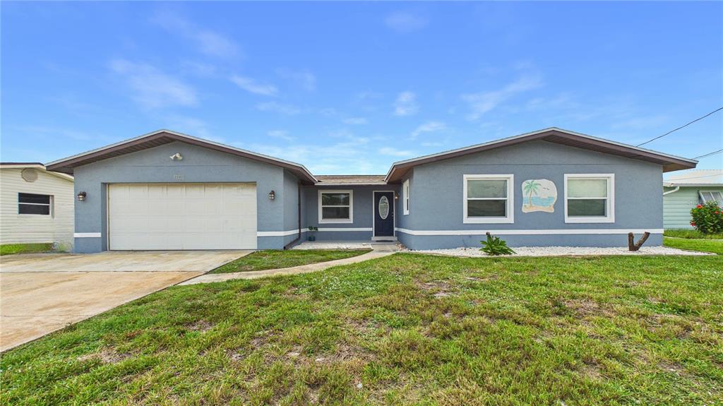 A single-story blue house with a two-car garage and a front lawn — 1545 W CORAL COURT, MERRITT ISLAND, FL