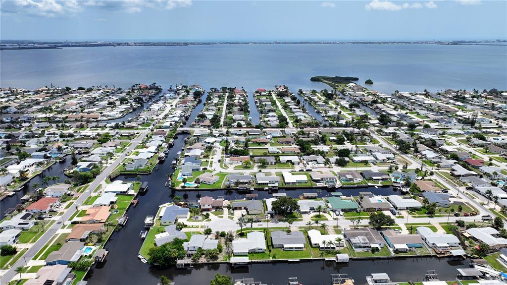 An aerial view shows a residential neighborhood with houses situated along canals leading to a bay — 1545 W CORAL COURT, MERRITT ISLAND, FL