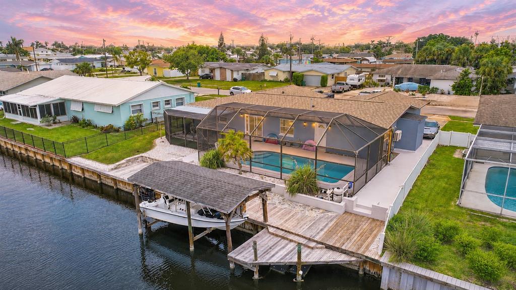 An aerial view of a waterfront house with a screened pool, boat dock, and deck — 1545 W CORAL COURT, MERRITT ISLAND, FL
