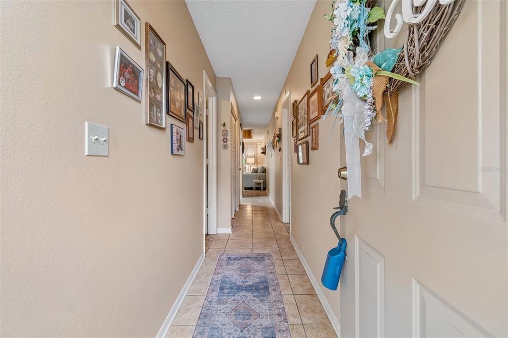 A hallway with tiled floors, a runner rug, and numerous framed pictures on the walls — 6100 TOPHER TRAIL, MULBERRY, FL