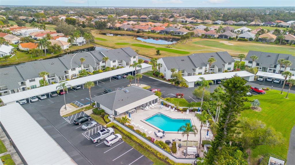 An aerial view of a residential complex featuring a swimming pool, parking, and golf course — 1100 CAPRI ISLES BOULEVARD UNIT 325, VENICE, FL