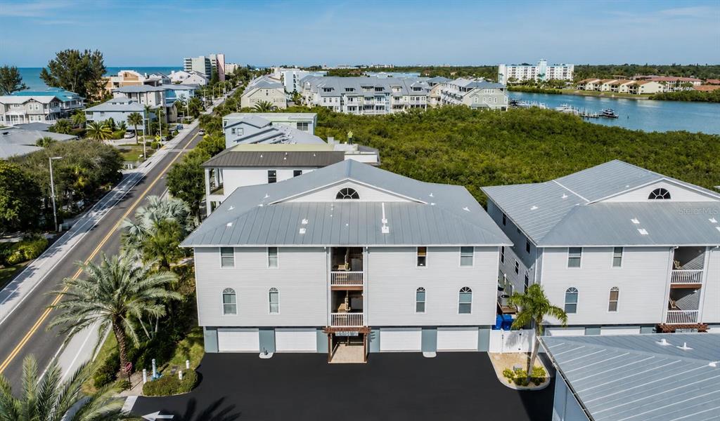 An aerial view shows a multi-story residential building with a metal roof and parking area — 19829 GULF BOULEVARD UNIT 103, INDIAN ROCKS BEACH, FL