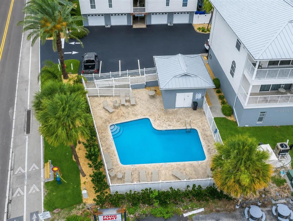 An open-concept living and dining area features a wooden table, leather sofas, and balcony access — 19829 GULF BOULEVARD UNIT 103, INDIAN ROCKS BEACH, FL