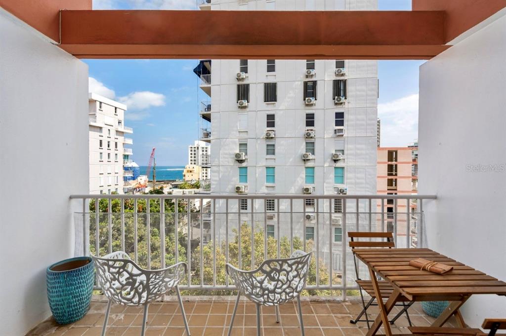 A dining room features a glass-topped table with a driftwood base and a kitchen pass-through — 1202 Av Magdalena MAGDALENA UNIT 702, SAN JUAN, PR